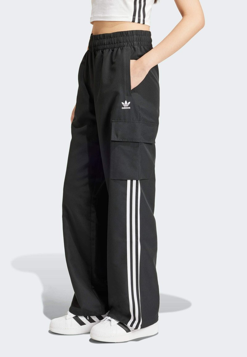Svarta cargobyxor med elastisk midja, sidofickor och tre vita ränder längs sidorna. Har en Adidas-logotyp på höften.