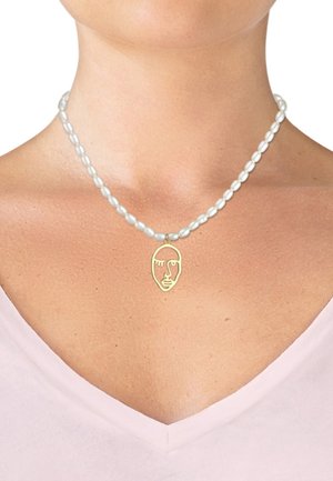 Perlenkette mit ovalen weißen Perlen und einem goldenen Anhänger in Gesichtsform, der mit filigranen Gesichtszügen und einer glatten Oberfläche gestaltet ist.