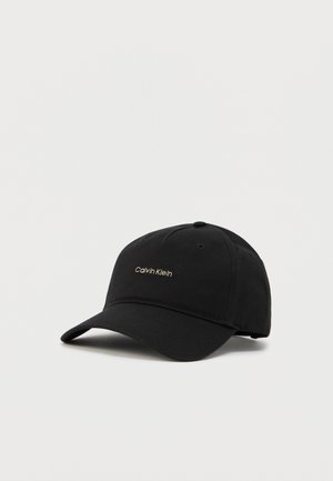 Black cotton cap featuring a curved brim, embroidered "Calvin Klein" logo in gold, and a structured crown with ventilation eyelets.
