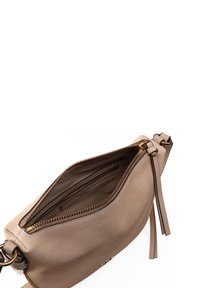 Beige Lederhandtasche mit Reißverschluss, ausgestattet mit einem Innenfach und einem Quasten-Detail an der Seite, glatte Textur und goldfarbener Hardware.