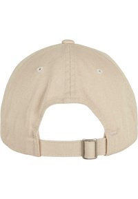 Gorra de algodón beige con visera curvada y correa ajustable en la parte posterior; presenta costuras visibles y una ojal de ventilación.