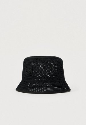 Juoda tinklinė kibiro formos kepurė su plačia, lankstžia pasauga ir tekstūruota paviršiaus. Priekyje yra subtilus iškilus logotipas. Lengva medžiaga.