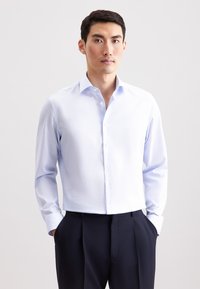 Lichtblauw overhemd met subtiele verticale strepen, lange mouwen en een spreidkraag, gecombineerd met donkere, op maat gemaakte broek.