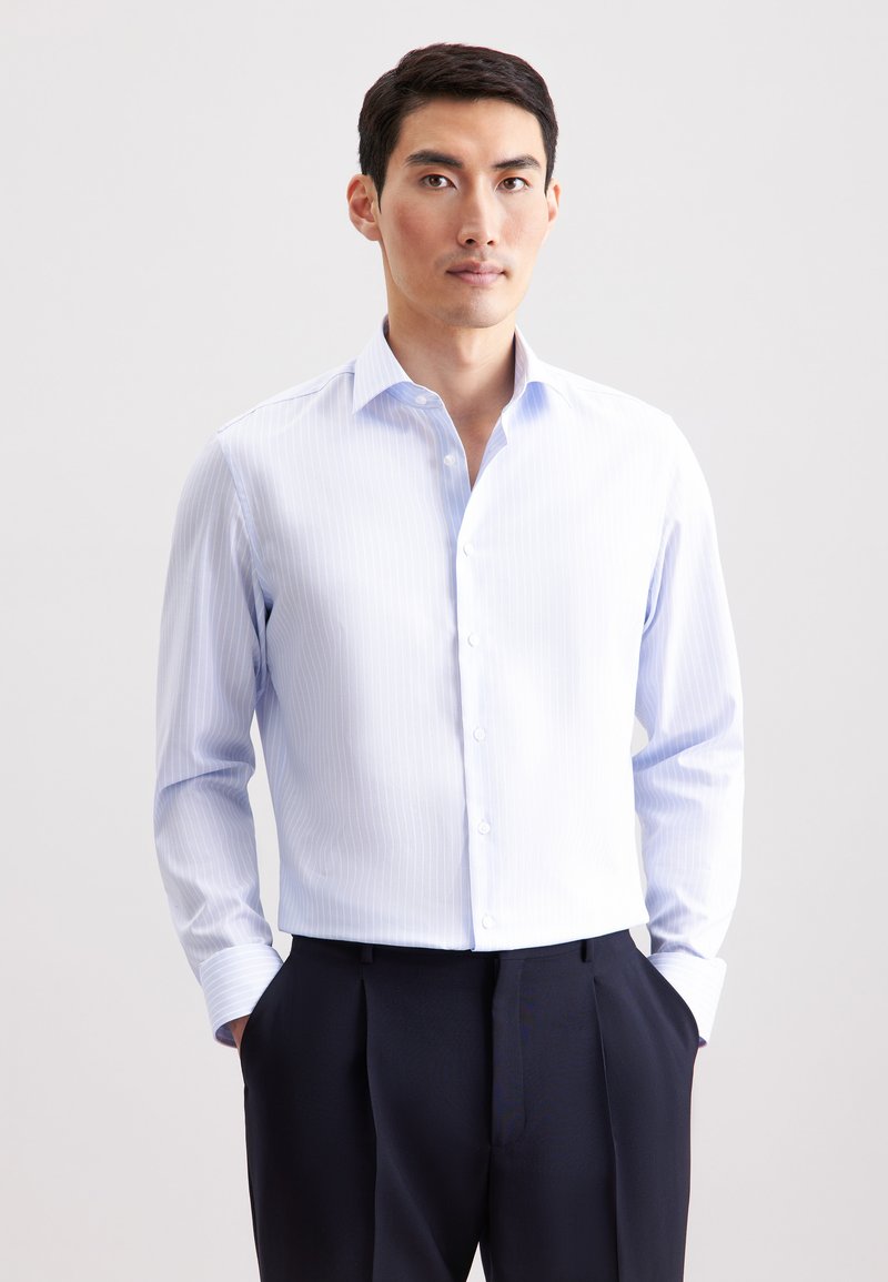 Lichtblauw overhemd met subtiele verticale strepen, lange mouwen en een spreidkraag, gecombineerd met donkere, op maat gemaakte broek.