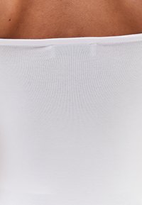 Top bianco senza maniche con una texture liscia ed elastica e un collo rotondo. Senza cuciture visibili o elementi di design aggiuntivi.