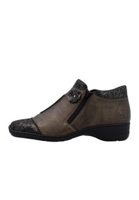 Bottine en cuir marron avec un embout noir texturé, fermeture éclair latérale, accent décoratif en forme de fleur et petit talon. Détails texturés au niveau du col.
