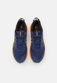 Blaue Sportschuhe mit einem Obermaterial aus Mesh, orangefarbenen Akzenten, schwarzem Innenraum und gelben Details an den Seiten und der Sohle. Schnürdesign.