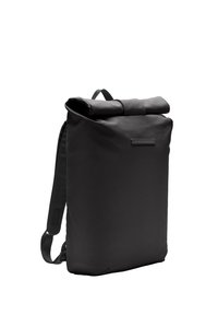 Sac à dos noir à rabat fabriqué en tissu durable, doté de sangles réglables, d'une texture lisse et d'un design minimaliste avec une petite poche avant.