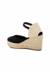Zapato de cuña espadrille negro con parte superior de ante, suela de yute trenzado y un acento de tela a cuadros en el talón. Incluye correas ajustables para el tobillo.