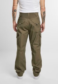 Pantalones cargo verdes con cintura elástica, bolsillos laterales y bolsillos traseros; confeccionados en tejido duradero con una textura suave.