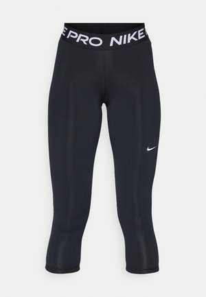 Czarne legginsy o dopasowanym kroju, z szerokim paskiem w talii z napisem "NIKE PRO" na biało oraz małym białym logo w kształcie łyżwy z boku.