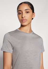 Camiseta cinza de manga curta com decote redondo e uma textura suave e macia. O tecido parece leve com um padrão heather sutil.