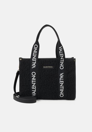Sac tote Valentino noir texturé avec de larges anses en tissu imprimées de "Valentino" en blanc et une bandoulière amovible.