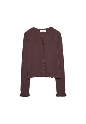 Vrouw draagt een bruine gebreide cardigan met knopen en gerimpelde randen over een wit topje, zichtbaar van nek tot taille.
