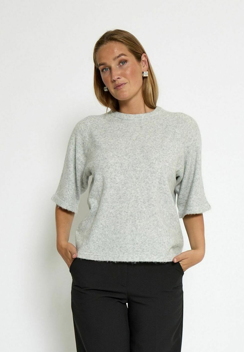 Light gray, short-sleeve sweater with a soft, textured finish and round neckline, paired with black pants. Simple and modern design.
