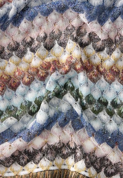 Tissu tricoté coloré avec un motif en forme d'écailles dans des tons bleus, blancs, roses, marrons, jaunes et verts, montrant la texture et les plis.