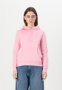Sweatshirt à capuche rose clair en tissu doux, avec une poche kangourou sur le devant et des poignets côtelés. Petit logo sur la poitrine.