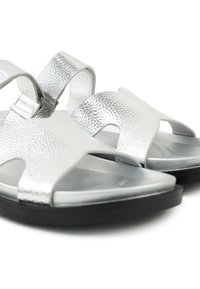 Silver textured open-toe sandals with slingback straps and black soles, shown in close-up on a white background.