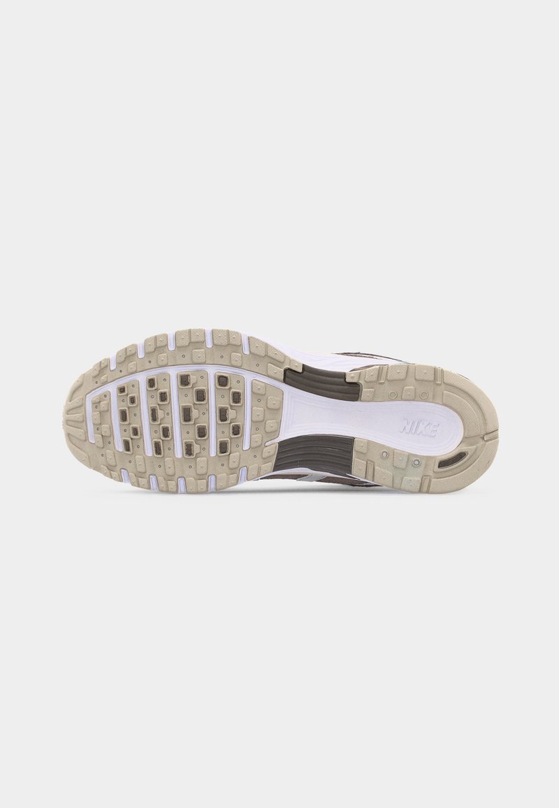 Semelle de sneaker Nike beige et blanche avec motif de bande de roulement texturé et logo Nike visible sur la section du talon.
