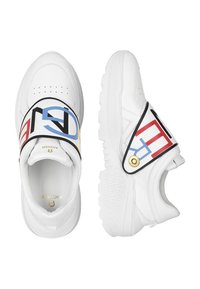 Baskets blanches avec une bride décorative ornée de lettres multicolores, une semelle texturée et un accent circulaire doré sur le côté.