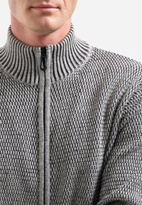 Grijze en zwarte zip-up trui met een textuurpatroon, hoge geribbelde kraag en ritssluiting aan de voorkant. Chunky breid ontwerp.