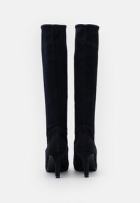 Bottes en daim bleu marine montant jusqu'au genou, avec une forme effilée, des talons hauts, des coutures visibles et une texture lisse. Sans accents ni détails supplémentaires.