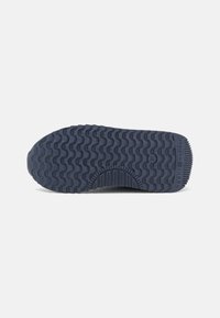 Semelle de chaussure en caoutchouc bleu foncé avec un motif ondulé, taille 31, et texte "Tommy Hilfiger" sur la section du talon.