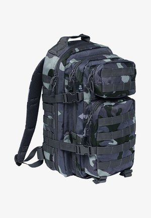 Kamuofliaus kuprinė su keliais užtrauktukais, reguliuojamais diržais ir horizontaliu webbing'u priedams tvirtinti. Pagaminta iš patvarios medžiagos.