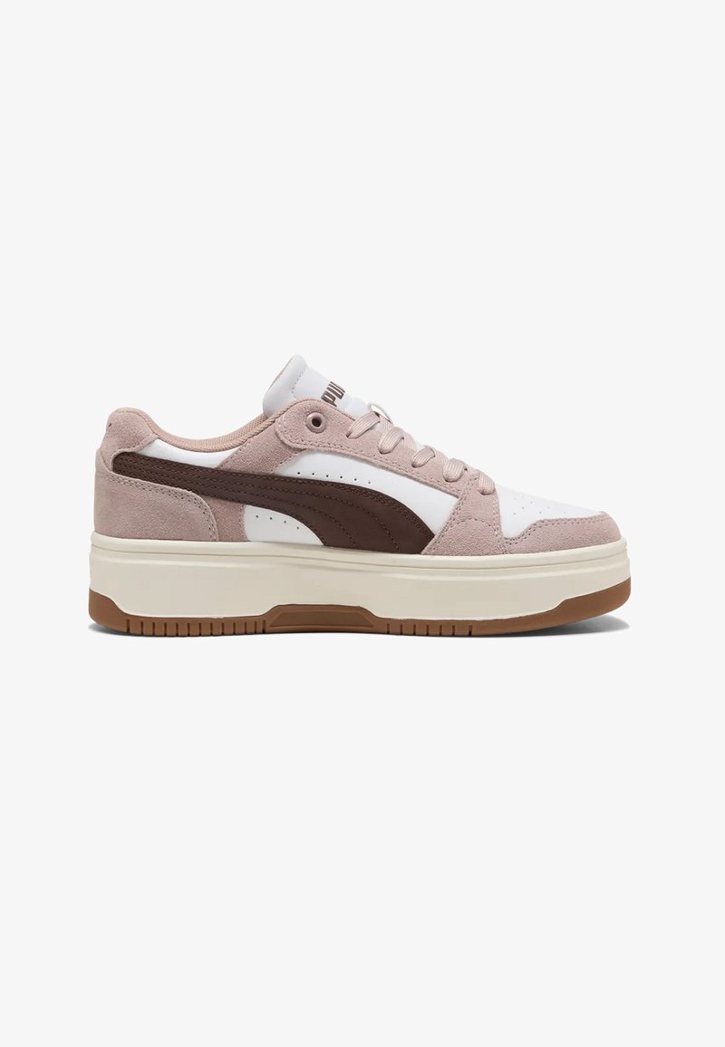 Lage sneaker met wit leer, lichtbruine suède overlays, een donkerbruine streep langs de zijkant en een dikke off-white zool met bruine profielzool.