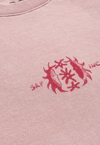 Różowa bluza z czerwonym nadrukiem z abstrakcyjnymi kształtami oraz napisem "SRF INC." Teksturalny materiał z prążkowanym dekoltem.