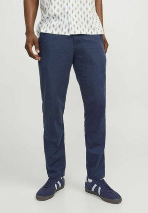 Chinos blu navy in tessuto leggero con taglio dritto, abbinati a sneaker scure con strisce azzurre.