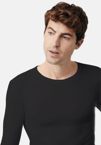 Camisa negra de manga larga hecha de tela ligera, con un cuello redondo y textura suave, diseño ajustado sin herrajes ni patrones visibles.