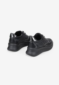 Baskets noires avec un dessus en cuir texturé, motif matelassé et un embout de talon noir brillant ; dotées de semelles en caoutchouc épaisses pour le soutien.