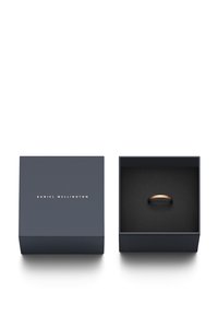 Okrogla rdeča zlata prstana, razstavljena v črni škatli, obloženi z belo barvo. Zunanjost škatle nosi napis "DANIEL WELLINGTON" v zlatem tisku.