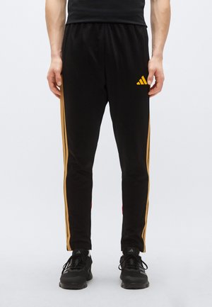 Mustad sportpüksid kollaste küljeribade ja logoga. Sile tekstuur, kitsenev lõige, elastne vöökoht ja soonikud mansetid.