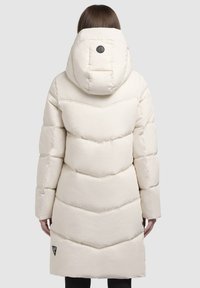 Witte pufferjas met een chevron-quiltontwerp, een grote capuchon en een logo-patch op de achterkant. Heeft een knielange snit en een soepele textuur.