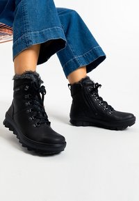 Botas de tobillo negras con cordones, borde de piel sintética, parte superior de cuero texturizado, collar acolchado y suela de goma resistente para una mejor tracción.