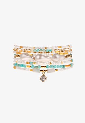 Bracelet multi-couches avec des perles dorées, blanches et turquoise, comprenant des perles irrégulières et un pendentif décoratif avec trois pierres.