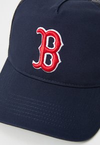 Cappellino da baseball Navy con un logo "B" ricamato in bianco e rosso, realizzato in un tessuto testurizzato con visiera curva e retro in rete.