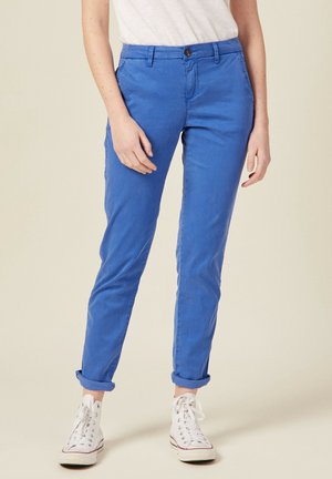 Blauwe katoenen chinos met een slim fit, featuring een knoopsluiting en opgerolde mouwen, gecombineerd met witte high-top sneakers.