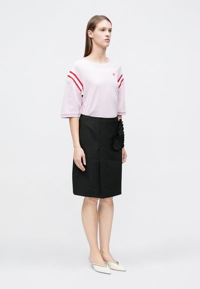 Ροζ ανοιχτό ροζ τζέρσεϊ μπλουζάκι με κόκκινες ρίγες, σε συνδυασμό με μαύρη φούστα μήκους έως το γόνατο με υφασμάτινη υφή και μαύρη λεπτομέρεια σε σχήμα λουλουδιού. Άσπρα μπαλαρίνες.