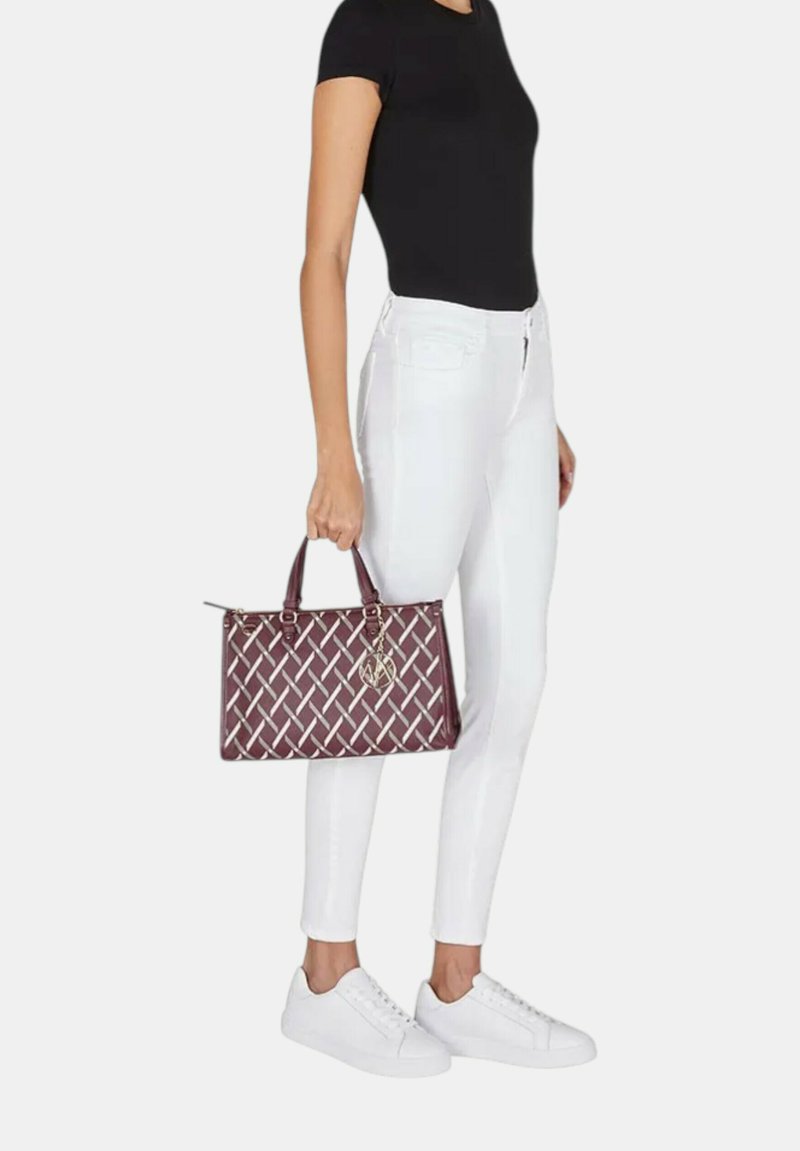 Borsa a tracolla bordeaux tessuta con motivo argento, manici superiori e dettagli in oro. Indossata con jeans skinny bianchi e sneakers bianche.