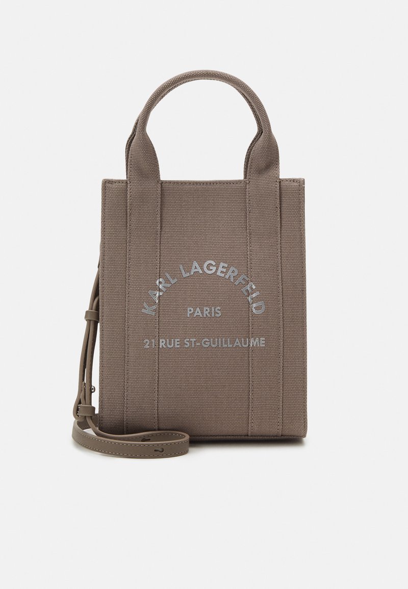 Bruine canvas totebag met dubbele handvatten en een afneembare schouderband. Voorzien van een bedrukte logo en tekst in zilver op de voorkant.