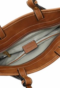 Borsa a mano di pelle color cuoio con un esterno in suede liscio, cuciture bianche a contrasto e un interno foderato che presenta una tasca con zip.