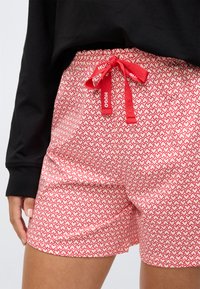 Rood-witte shorts met een patroon van kleine hartjes, voorzien van een elastische tailleband en een rode trekkoord met "HUGO" merklabel.