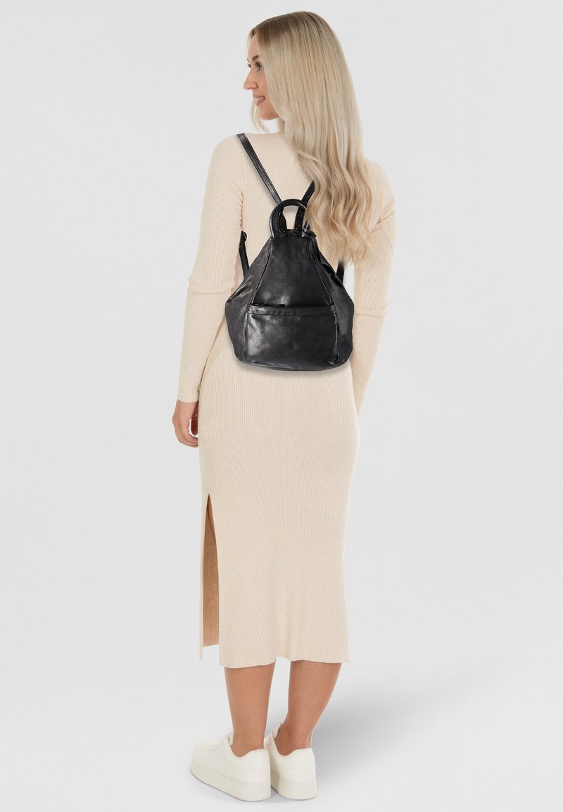 Schwarzer Leder-Rucksack in dreieckiger Form, mit einem oberen Tragegriff, verstellbaren Schulterriemen und einer Vordertasche. Glatte Oberfläche, minimale Hardware.