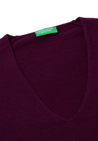 Sweter w serek w głębokim fioletowym odcieniu z mieszanki wełny, charakteryzujący się gładką fakturą oraz zieloną metką z napisem "United Colors of Benetton" wszytą przy dekolcie.