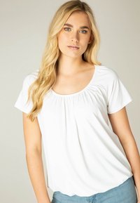 Witte top met korte mouwen en een ronde halslijn, voorzien van geplooide details aan de voorkant. Zachte stof valt losjes met een ontspannen pasvorm.