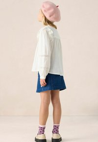 White long-sleeve blouse with lace accents, blue denim skirt, pink beret, and purple socks with black heart patterns. Black shoes.