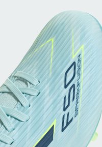 Chaussure de football bleu clair avec lacets, dessus texturé, accents en zigzag jaune fluo, et inscription "F50 Sparkfusion" en noir sur le côté.